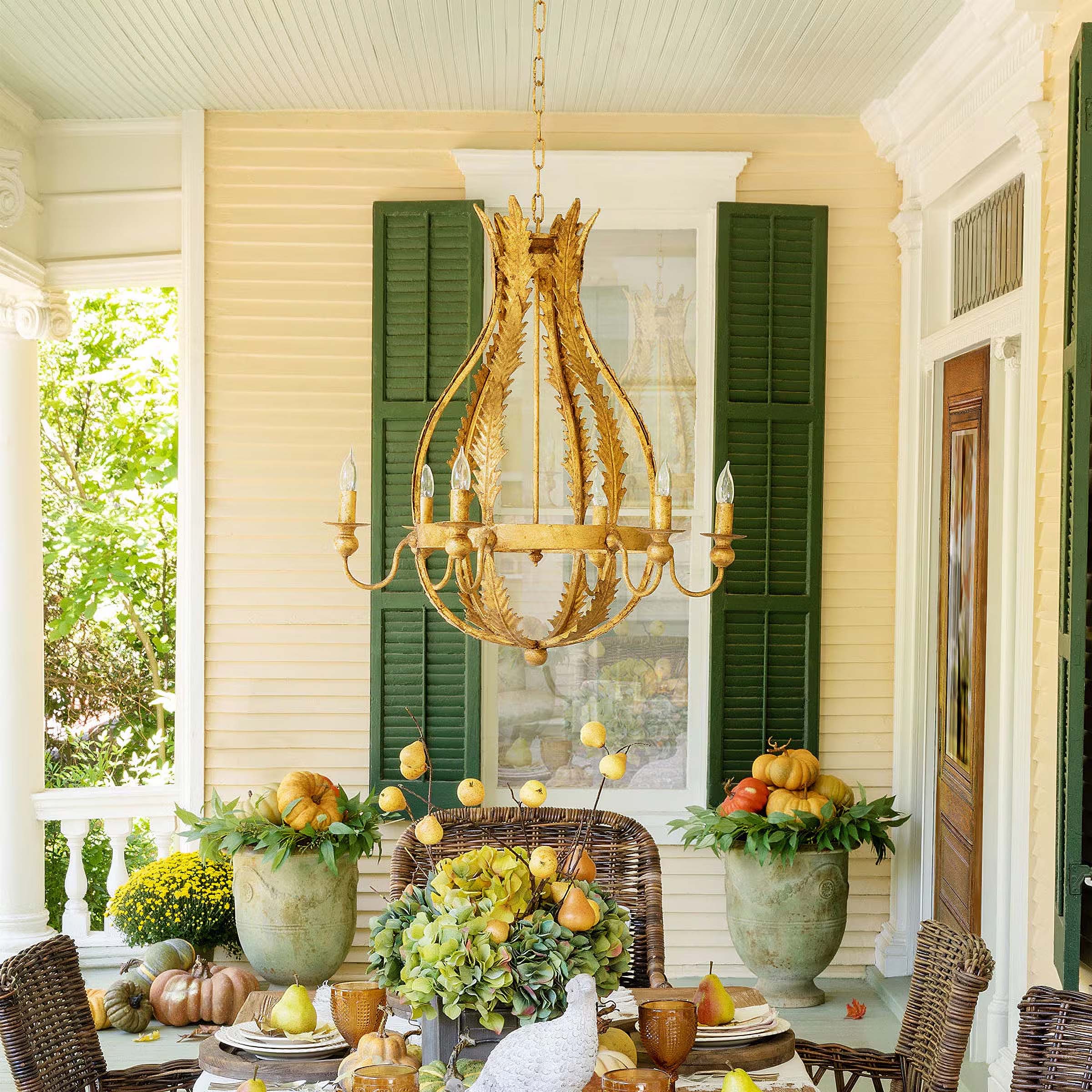 Antique-style vintage chandelier hanging in a beautifully decorated outdoor patio with elegant dining setup.
