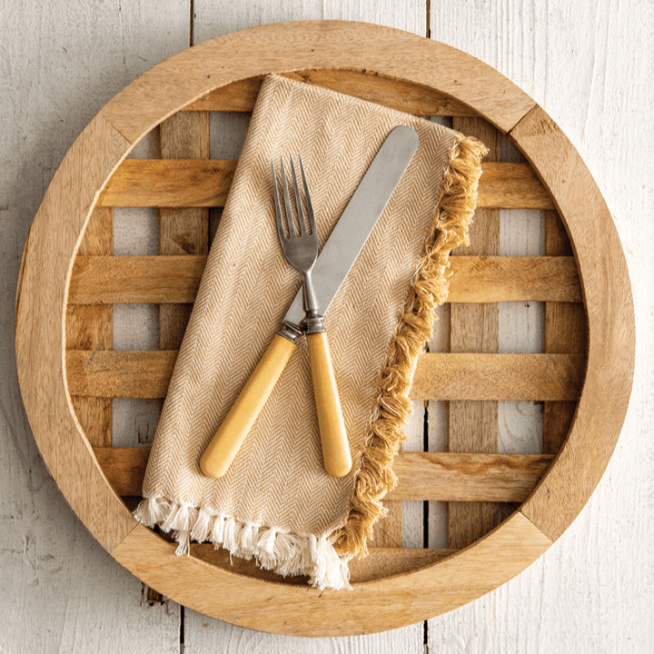 Farmhouse wood charger plate with slatted design, paired with vintage silverware on a fringed napkin.