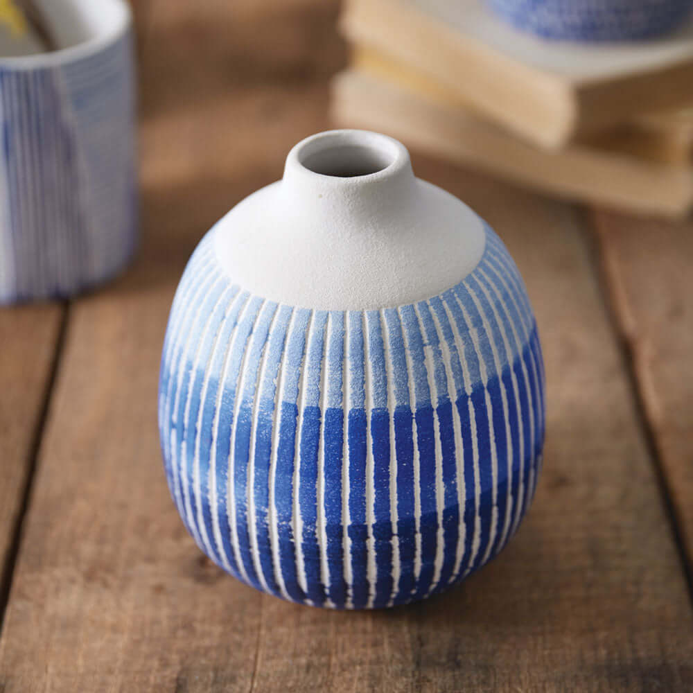 Textured blue and white ceramic bud vase on wooden surface, perfect for small floral arrangements or decorative display.