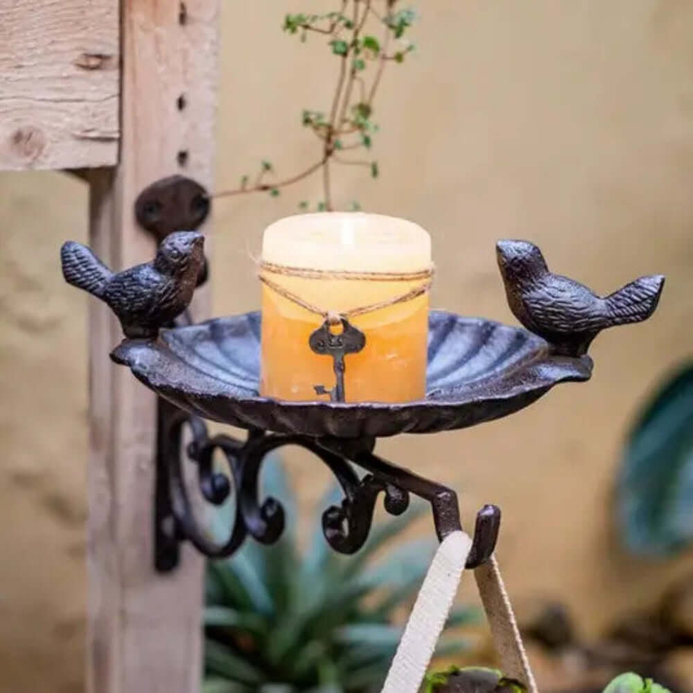 Antique-style wall-mounted bird feeder with two birds and a candle holder in a rustic design.