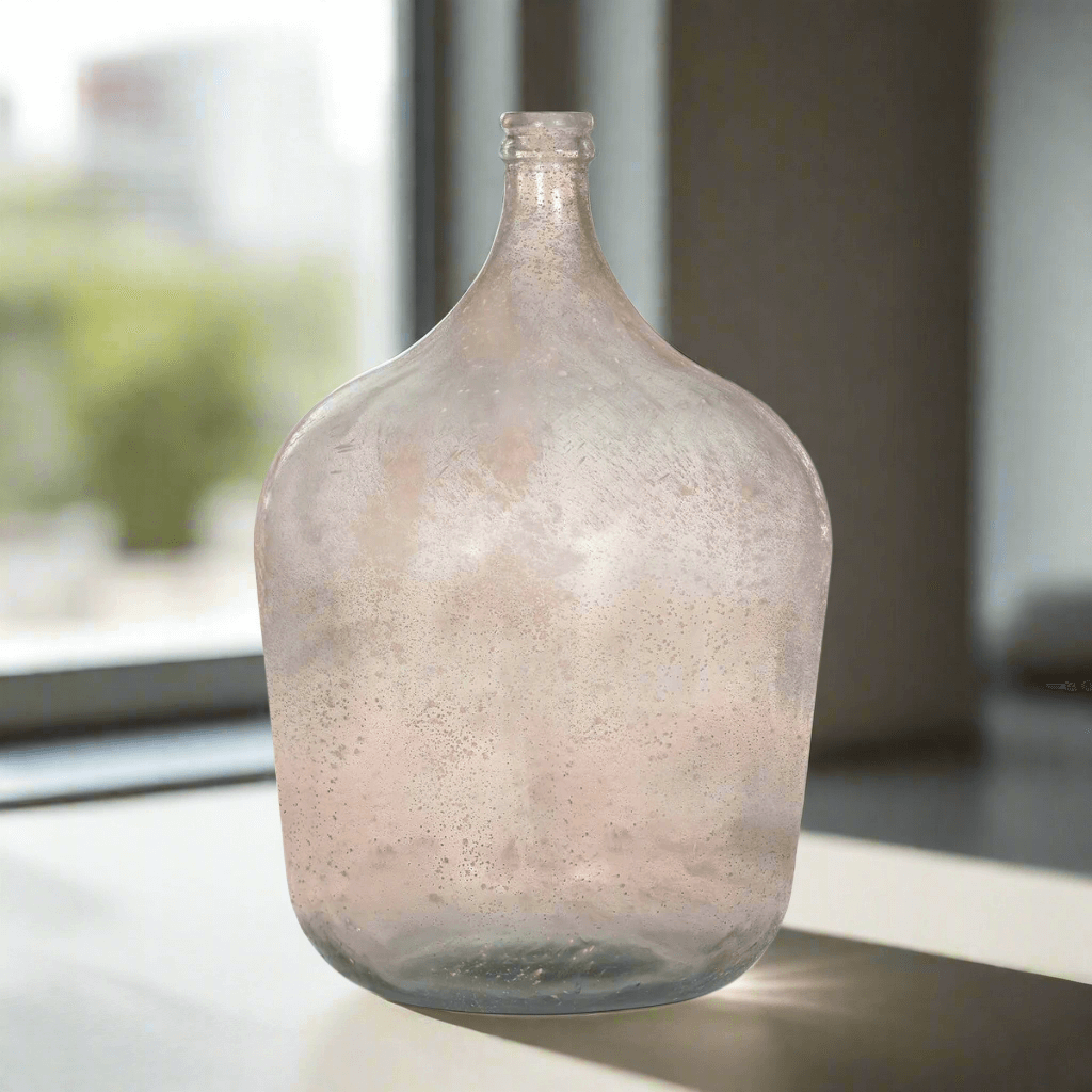 Vintage demijohn glass bottle vase in antique green on a windowsill, inspired by old-world vineyards. Hand-blown look with rustic charm.