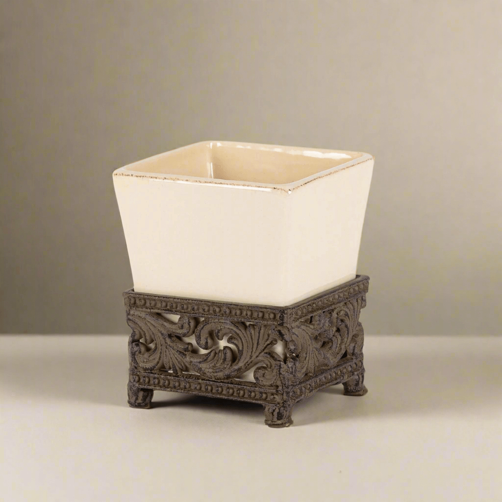 Victorian ceramic vase with ornate acanthus leaf metal base, square cream vessel, antique bronze finish. Elegant decor piece.