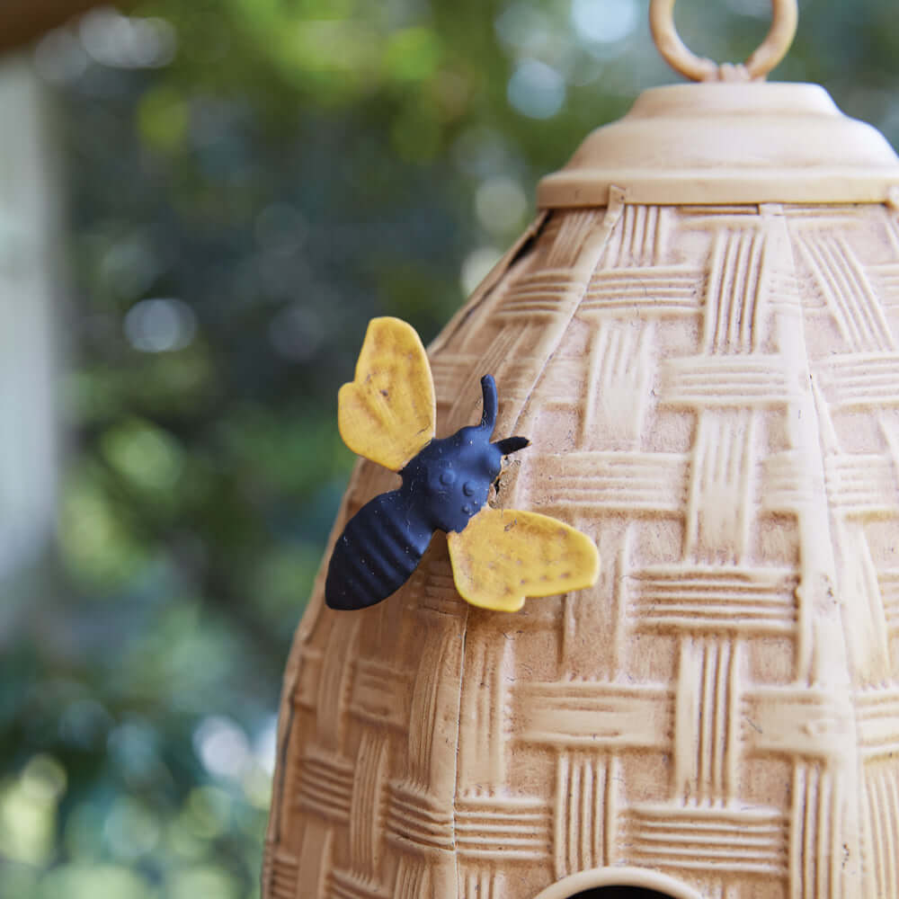 Cute bee figurine perched on a farmhouse-style beehive birdhouse, adding charm to your outdoor space.