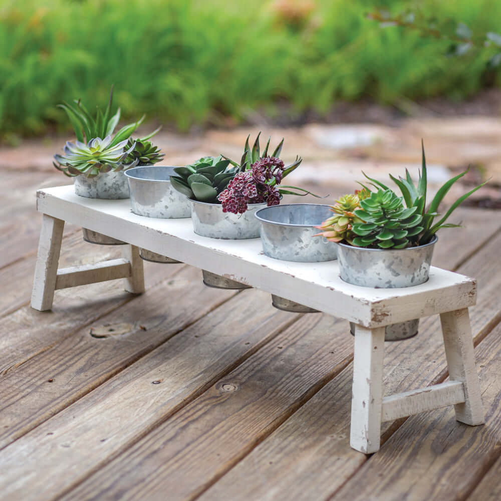 Rustic farmhouse bench planter with galvanized pots showcasing succulents and flowers on a wooden deck.