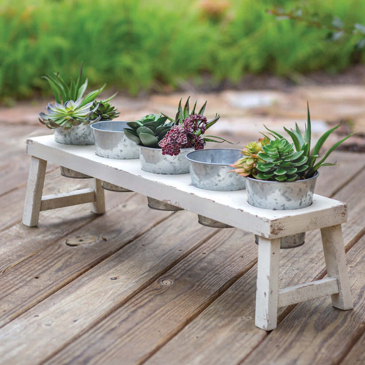 Rustic farmhouse bench planter with galvanized pots showcasing succulents and flowers on a wooden deck.