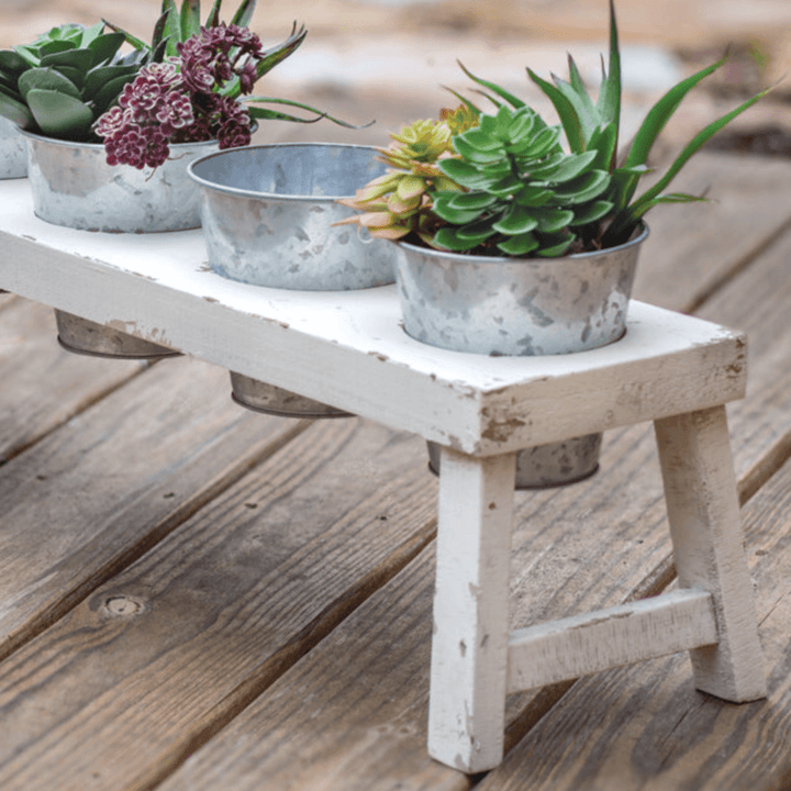 Rustic farmhouse bench planter with galvanized pots holding succulents, adding country charm to any space.