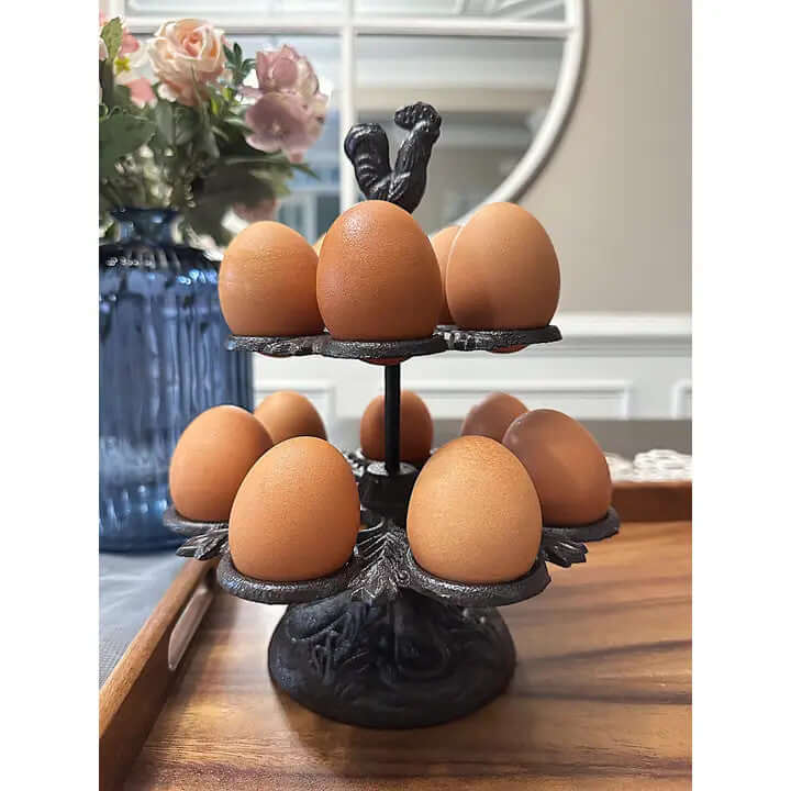 Rustic farmhouse cast iron two-tier egg holder with rooster design and brown eggs on a countertop.