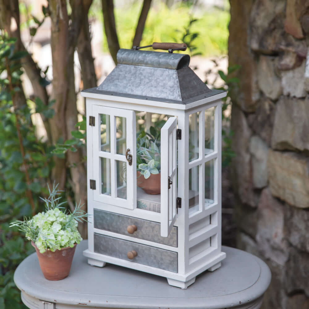 Rustic farmhouse greenhouse lantern with drawers, whitewashed wood, and zinc top, perfect for decor and plants.