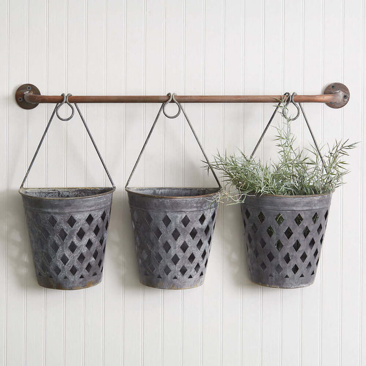 Rustic hanging lattice basket planters mounted on a copper rod, displaying greenery for home or garden decor.