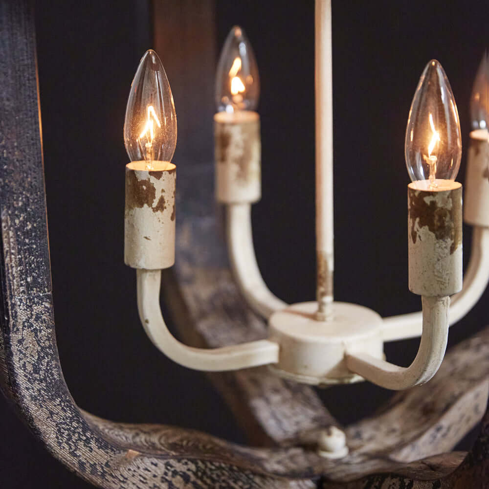 Close-up of a Rustic Vintage Farmhouse Chandelier with distressed white finish and candle-like lights, adding elegance to decor.