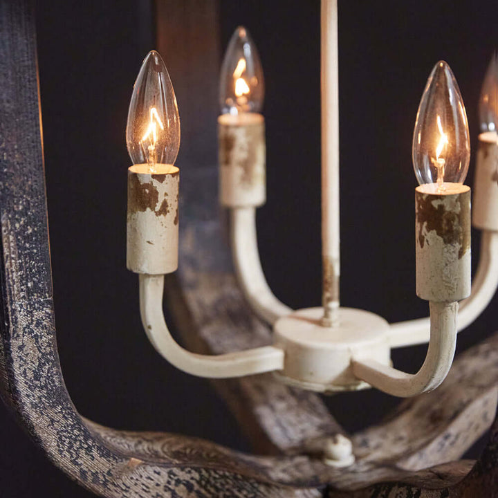 Close-up of a Rustic Vintage Farmhouse Chandelier with distressed white finish and candle-like lights, adding elegance to decor.