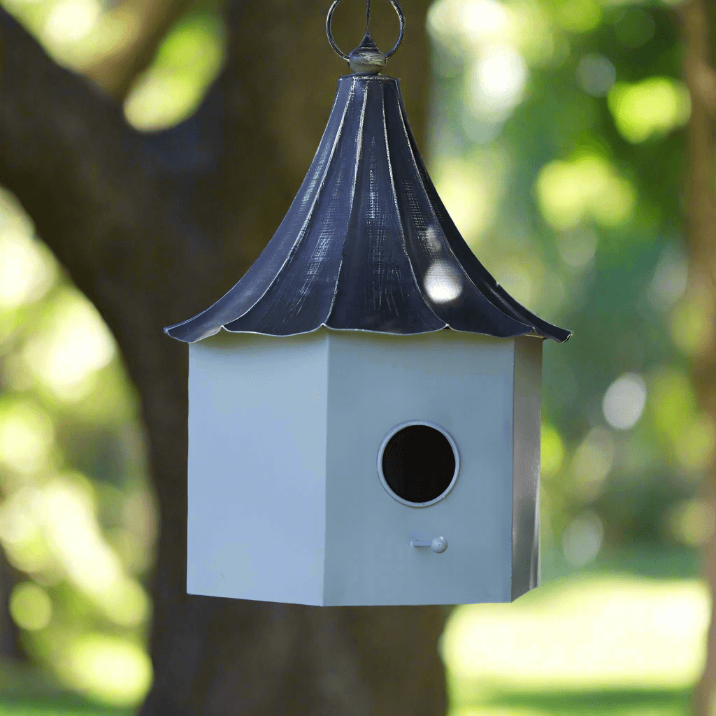 Victorian birdhouse with a distressed metal roof, capturing 19th-century charm in a serene garden setting.