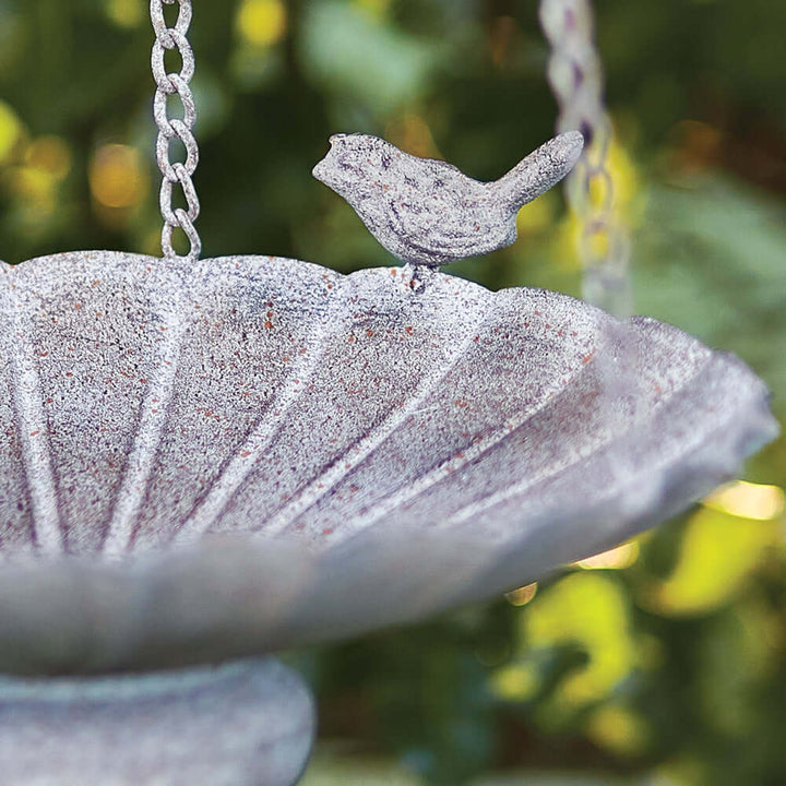 Close-up of a Victorian hanging bird feeder with tiered basins and a decorative bird figure.