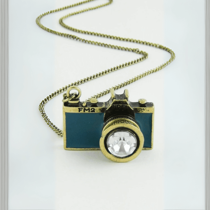 Vintage Camera Pendant Necklace with antique brass finish and teal enamel body, featuring a sparkling crystal lens on a chain