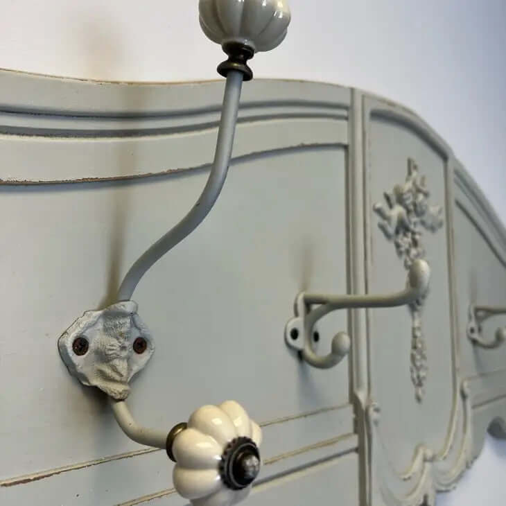 Vintage French country wall-mounted coat rack with ornate carvings and distressed green finish, ideal for farmhouse interiors.
