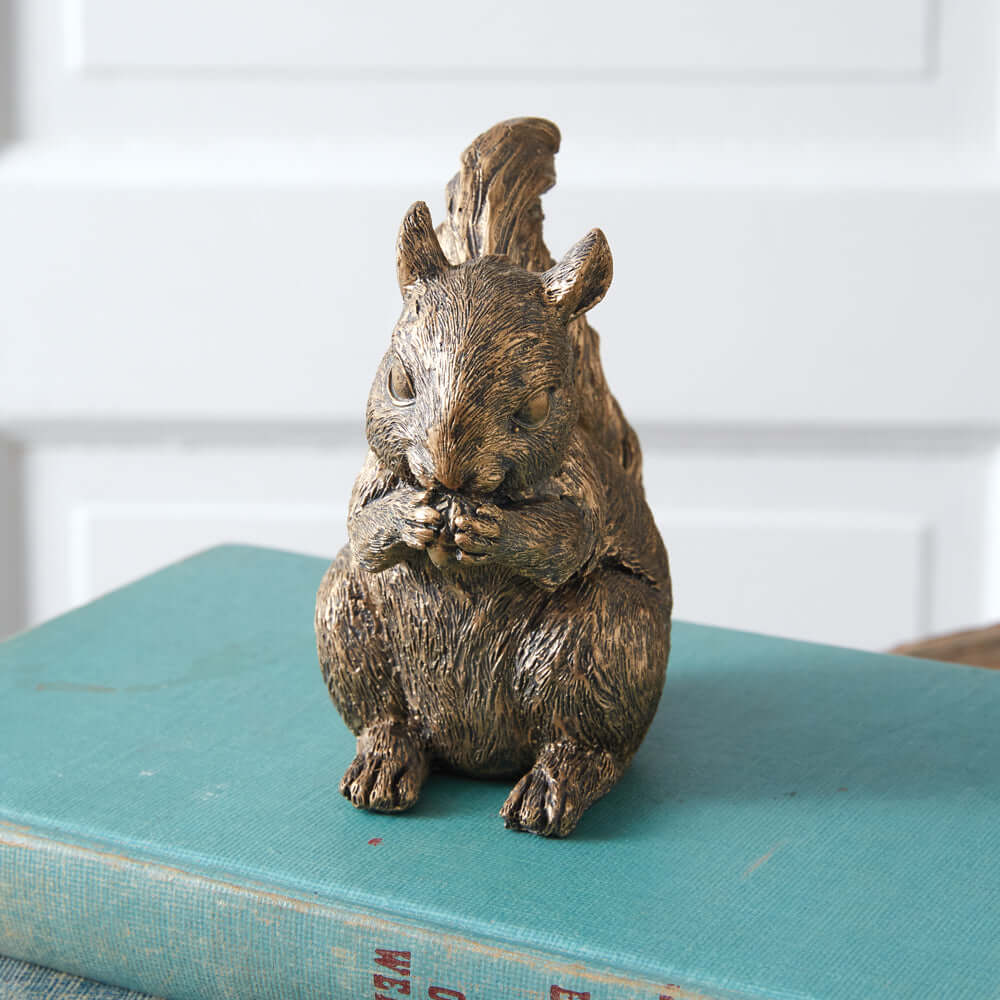 Antique bronze squirrel figurine on a vintage book, adding woodland charm to home décor.
