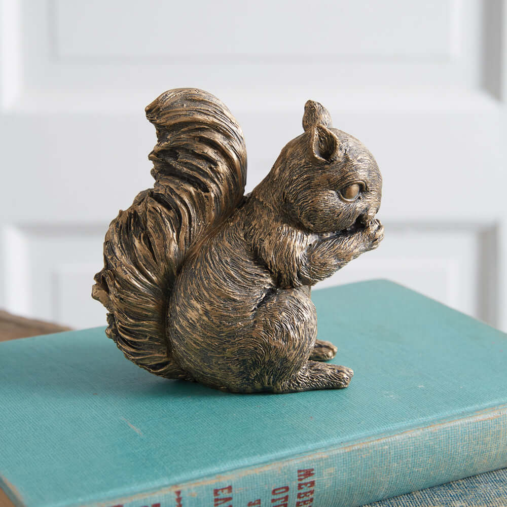 Antique bronze squirrel figurine resting on a stack of books, showcasing vintage decor elegance and woodland charm.