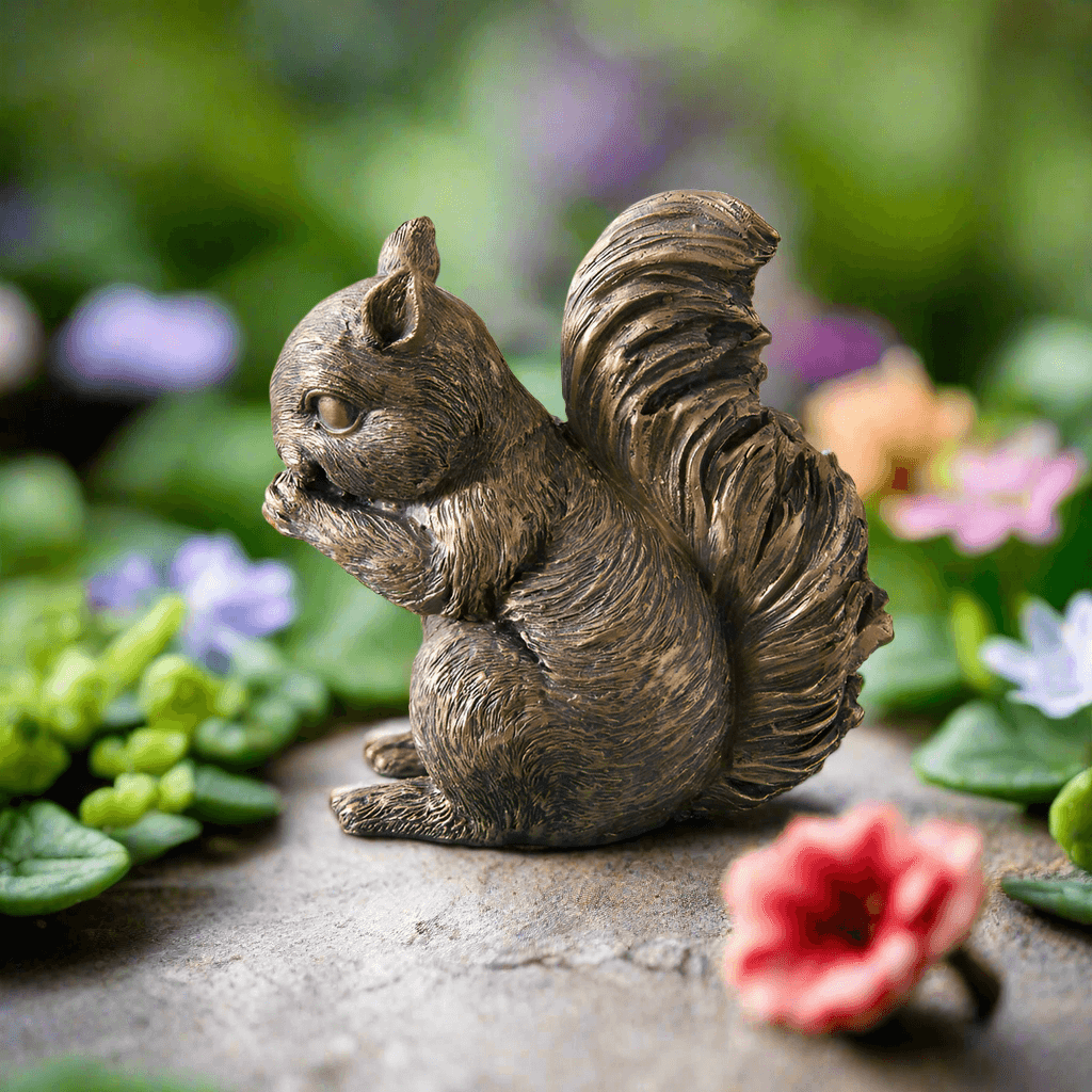 Antique bronze squirrel figurine among colorful flowers, showcasing vintage charm and woodland elegance.