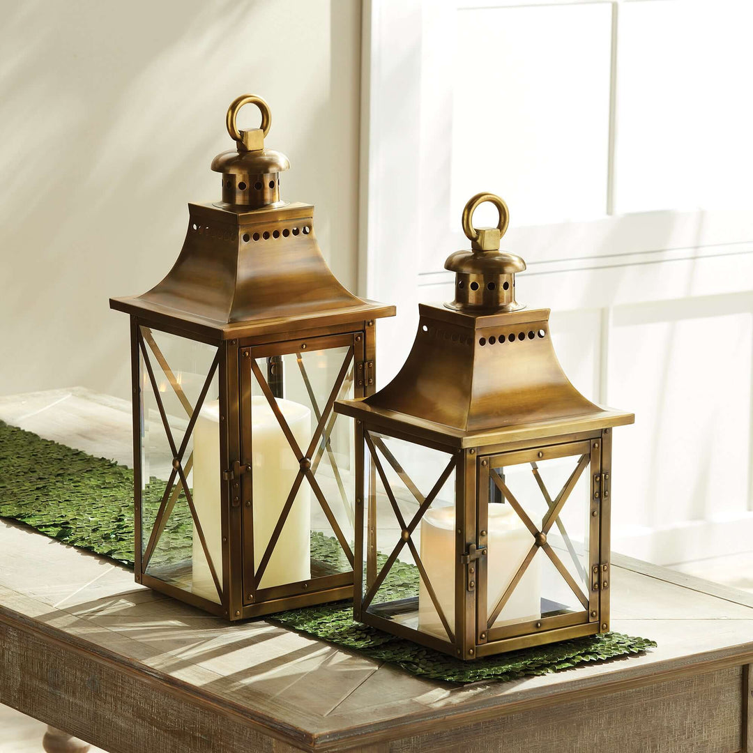 Antique brass lantern with crossbar glass and hanging ring, reflecting vintage carriage charm on a sunlit table.