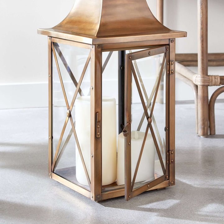 Antique brass lantern with crossbar glass, exuding vintage charm with its elegant design and warm reflective glow.