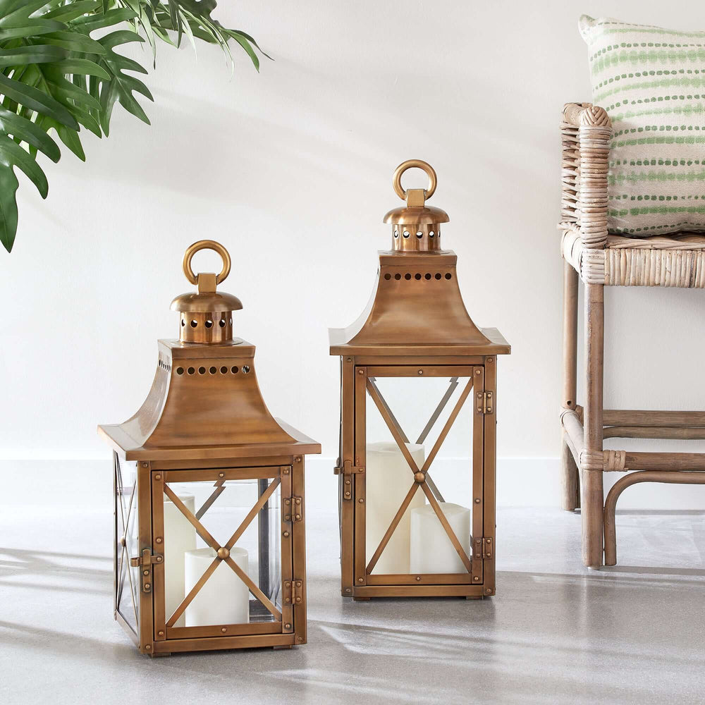 Antique brass lanterns with crossbar glass and hanging ring, exuding vintage charm and warmth, perfect for home decor.