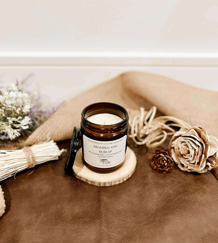 Bramble and Burlap Scented Candle: Elderberry, Oak & Vanilla on rustic table with floral decor.