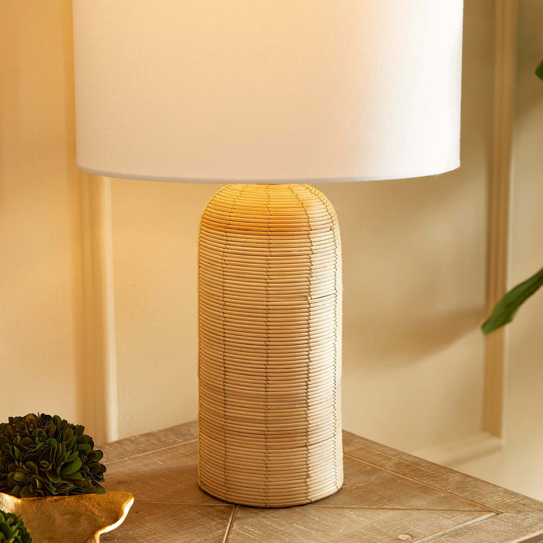 Coastal woven rattan table lamp with white drum shade, adding a light, airy ambiance to any space.