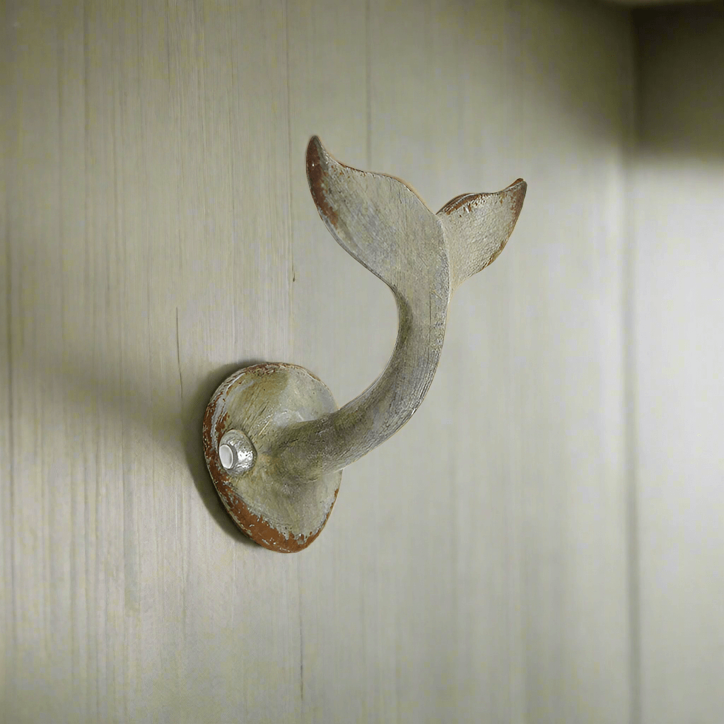 Distressed metal whale tail wall hook, perfect for coastal decor and adding nautical charm to any space.