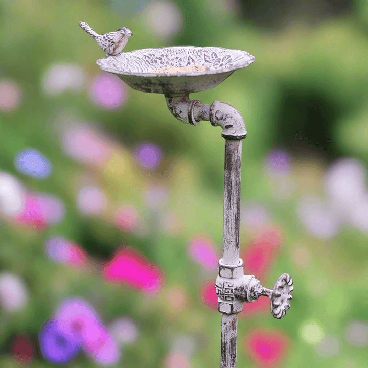 Farmhouse spigot garden stake bird feeder with vintage plumbing design and a small bird perched on the bowl.