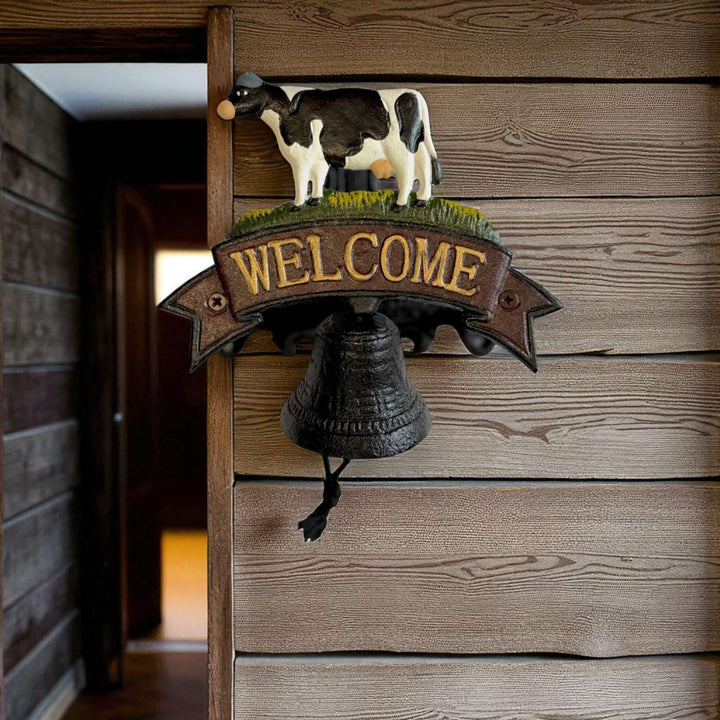 Farmhouse Cast Iron Cow Welcome Sign with Bell on rustic wooden wall.