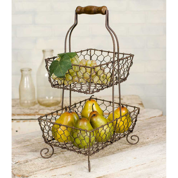 Farmhouse chicken wire two-tier fruit basket with pears and grapes, rustic metal design, wooden handle, vintage kitchen decor accent.