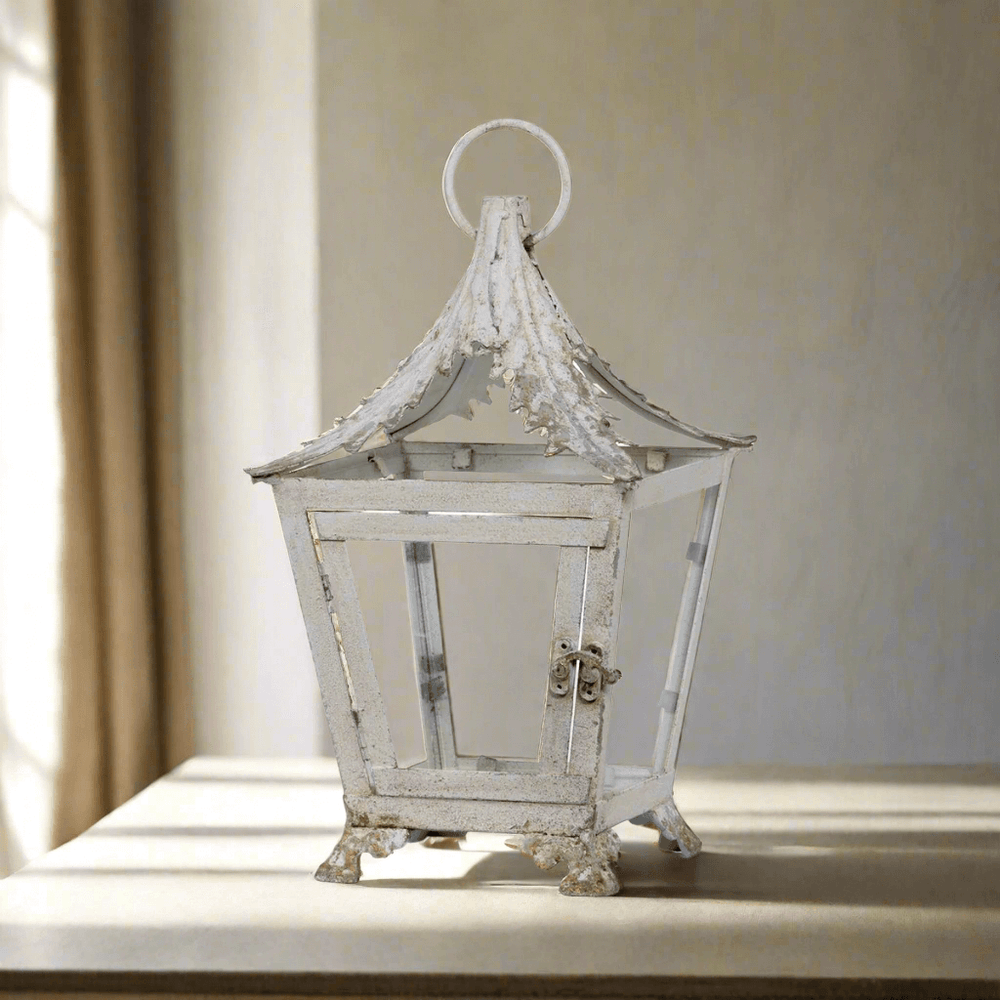 French Country Garden Lantern in distressed cream on a sunlit table, evoking Provencal romance with iron and glass craftsmanship.