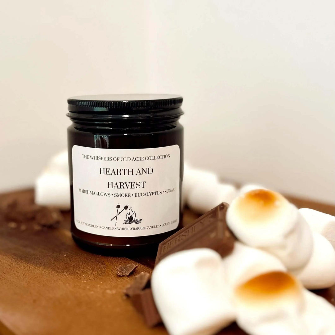 Hearth and Harvest Scented Candle: Marshmallow, Smoke & Eucalyptus with marshmallows and chocolate on a wooden board.