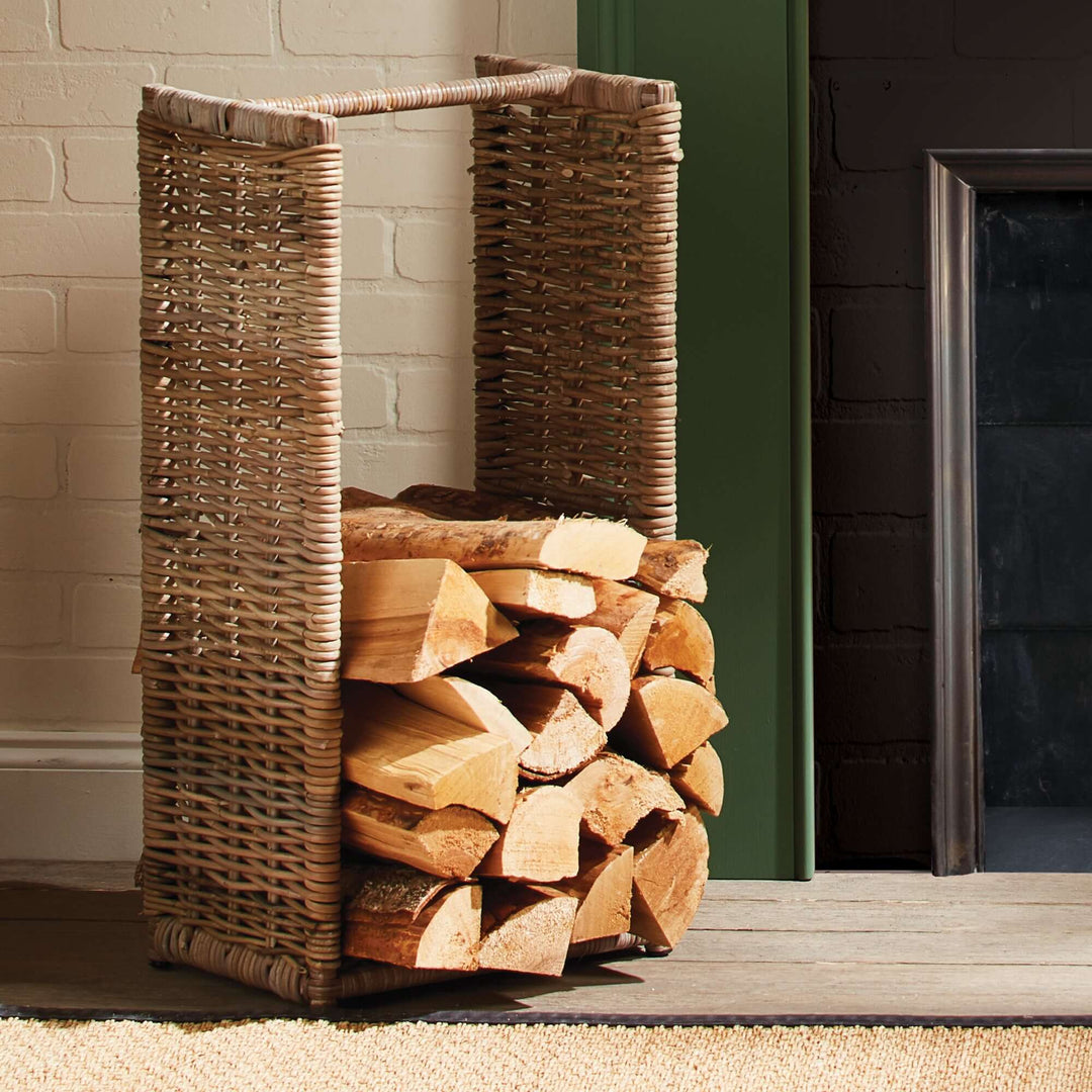 Natural wicker log basket for fireplace storage, showcasing stacked firewood in a cozy indoor setting.