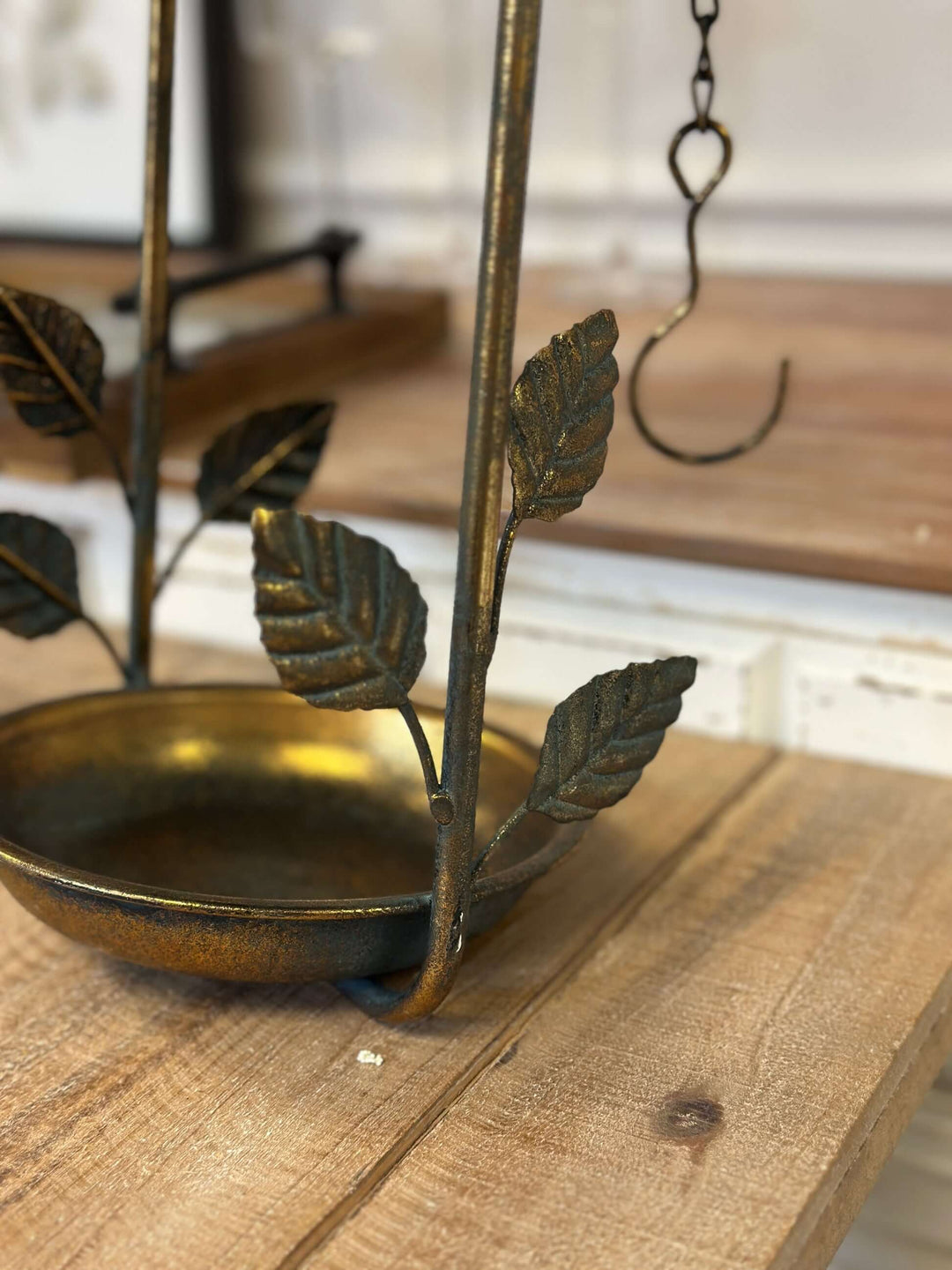 Rustic bronze hanging bird feeder with leaf design on wooden table, featuring a vintage metal finish and decorative bird elements.