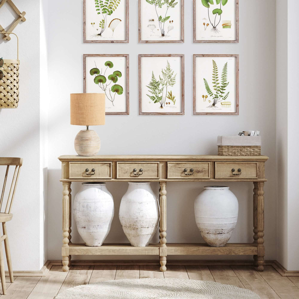 Rustic mango wood table lamp with linen shade on a console table, surrounded by antique pots and botanical art.