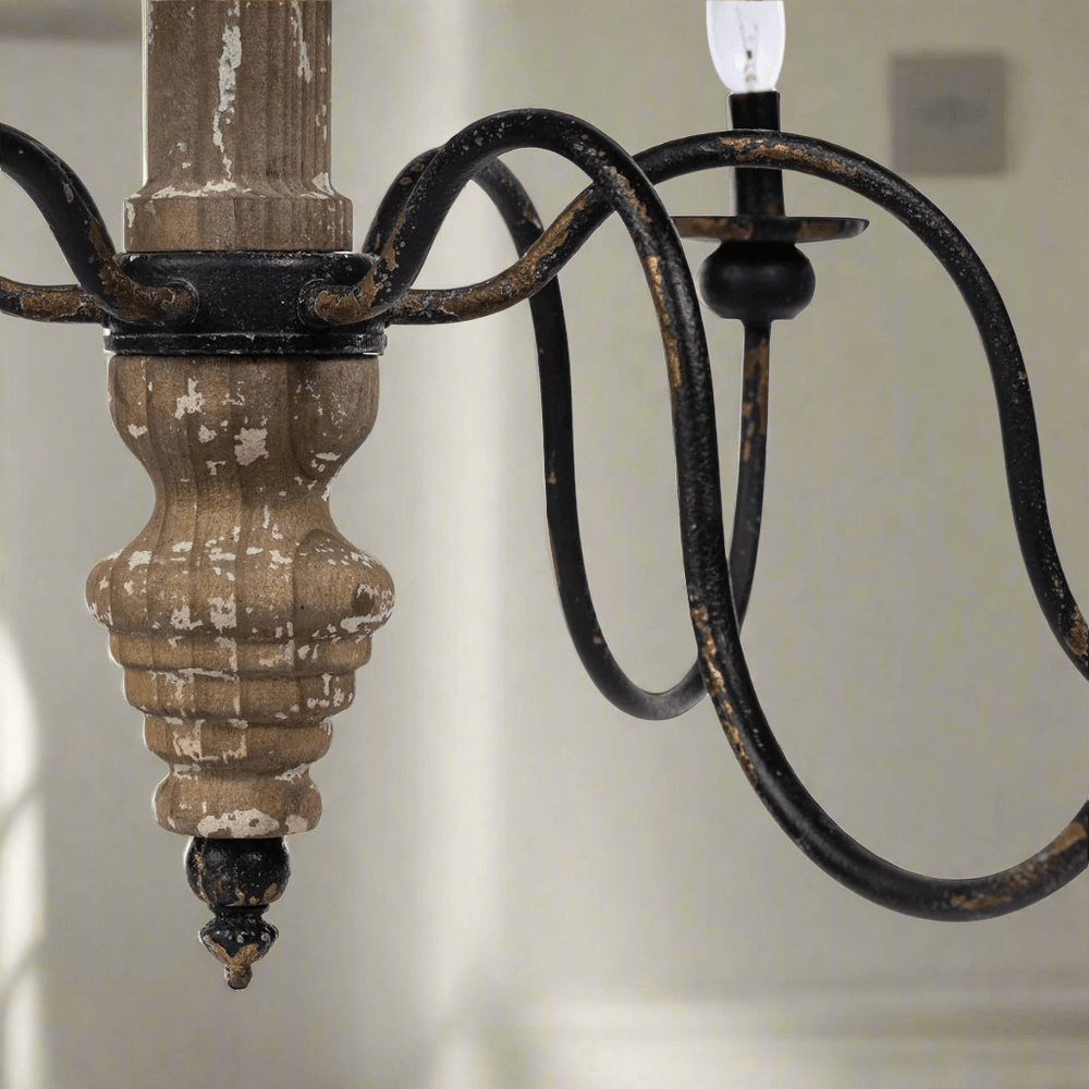 Rustic French Country chandelier close-up with distressed wood and black iron arms, evoking old-world charm and elegance.