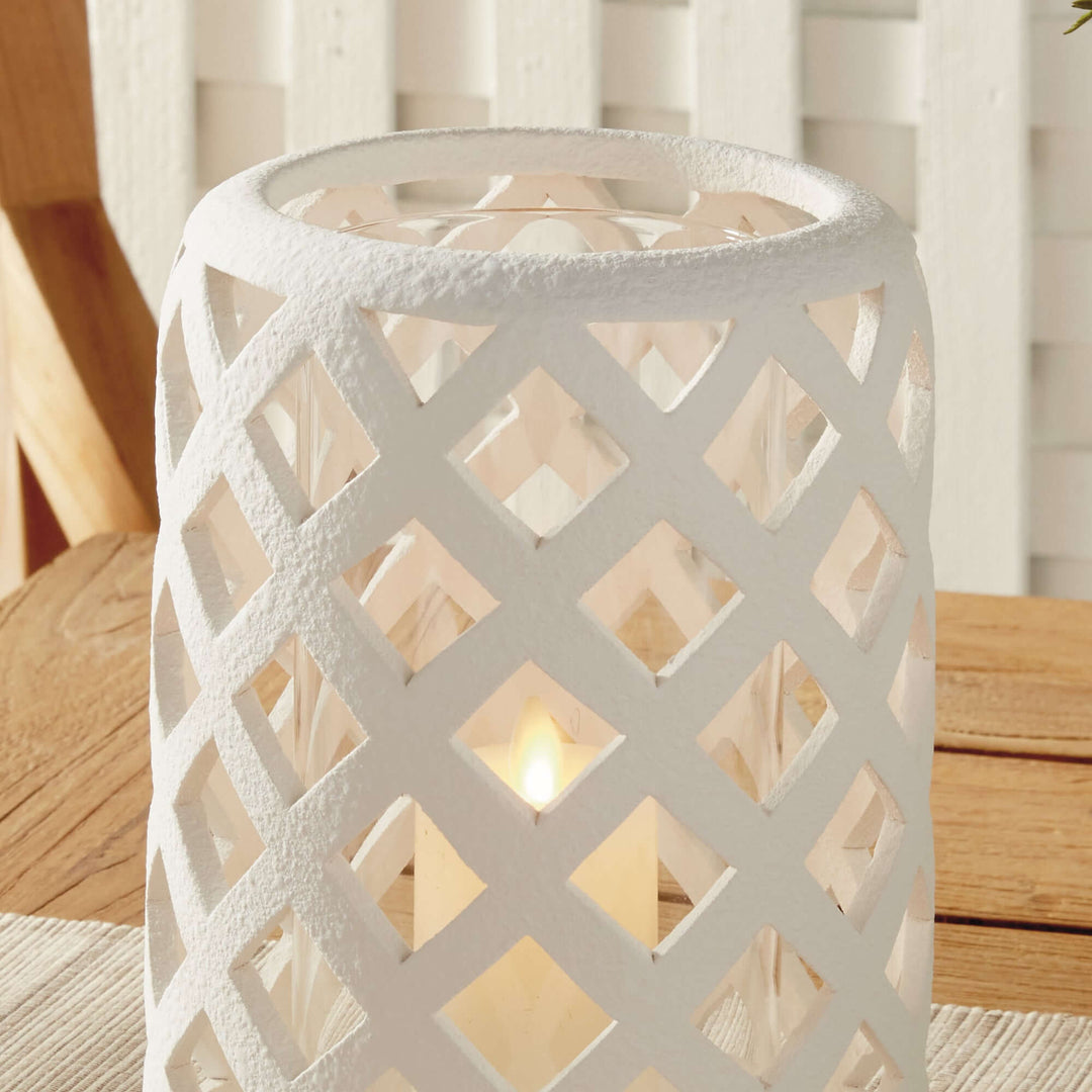 Terracotta hurricane candle holder with glass insert, featuring a lattice design and soft candlelight glow.