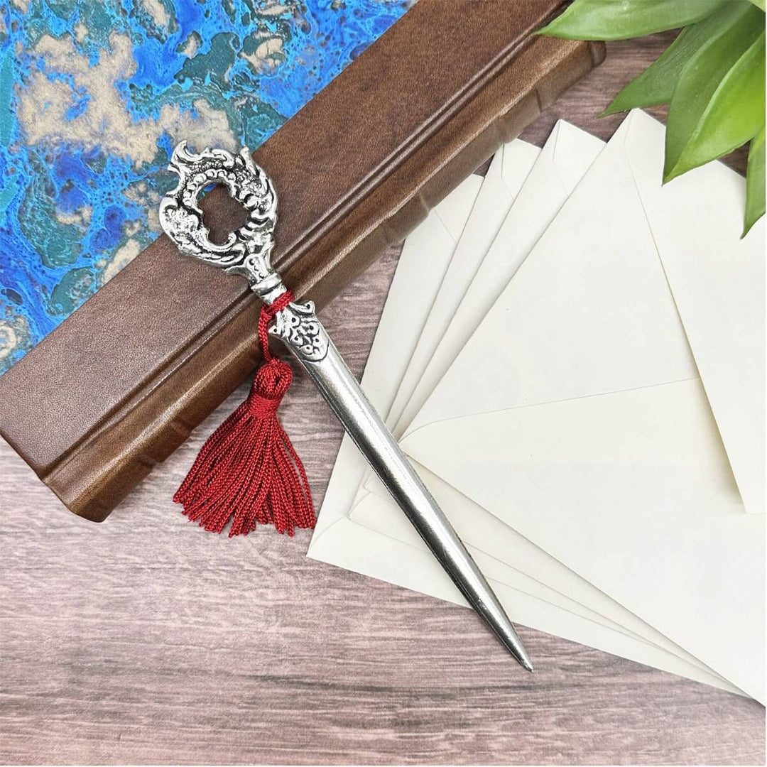 Victorian Letter Opener on wooden desk with envelopes, featuring intricate design and red tassel.