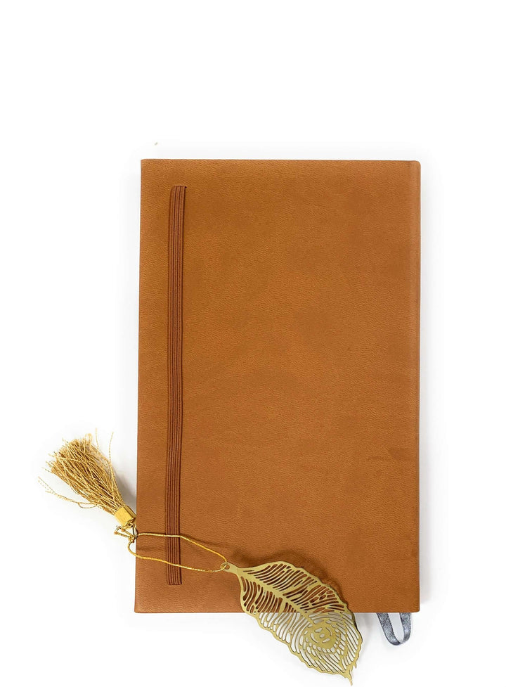Vintage Brass Feather Bookmark with Tassel (Set of 6) beside a closed brown leather journal, showcasing elegant design and golden finish.