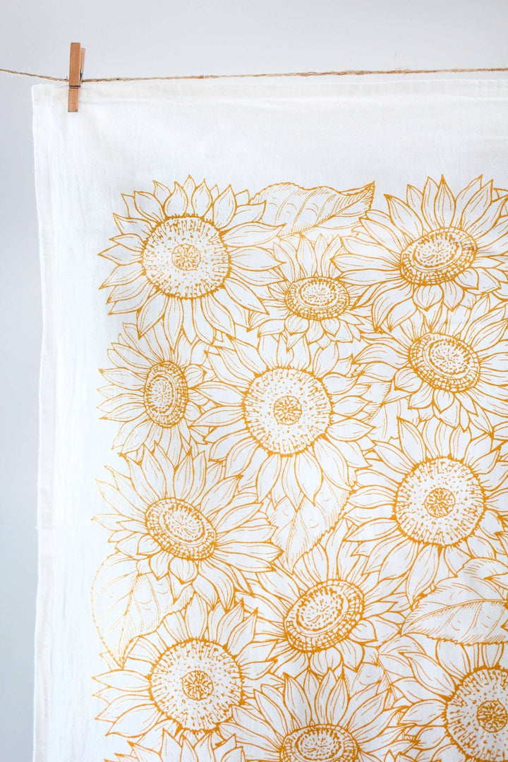 Vintage Sunflower Tea Towel with golden watercolor sunflower designs hanging on a line, capturing warm, rustic farmhouse charm.
