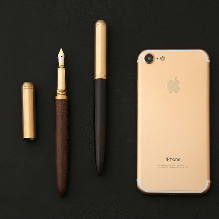 Vintage Wood and Brass Fountain Pen | The Hemmingway alongside a smartphone on a black surface