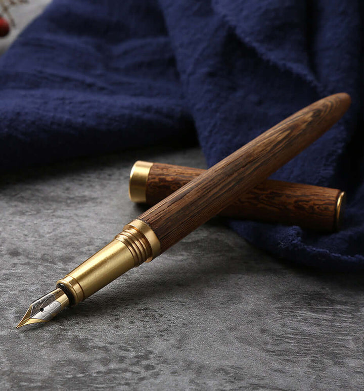 Vintage Wood and Brass Fountain Pen | The Hemmingway on a gray surface with blue fabric background.