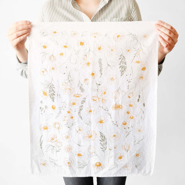 Female holding a Vintage Botanical Flower Garden Tea Towel with golden and green watercolor flowers.