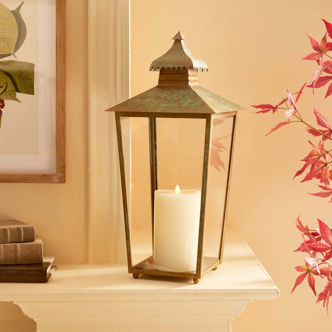 Vintage pagoda-top lantern with warm candle glow, evoking nostalgia in a mossy green and bronze patina.