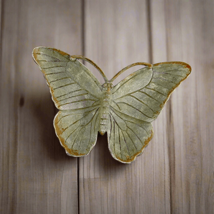 Vintage pewter butterfly trinket dish with antique zinc finish on wood surface, showcases nostalgic charm and delicate design.