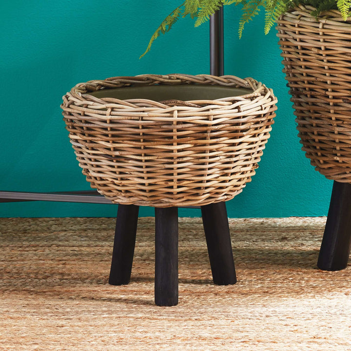 Woven rattan planter with wood legs, showcasing natural texture and modern design for stylish greenery display.