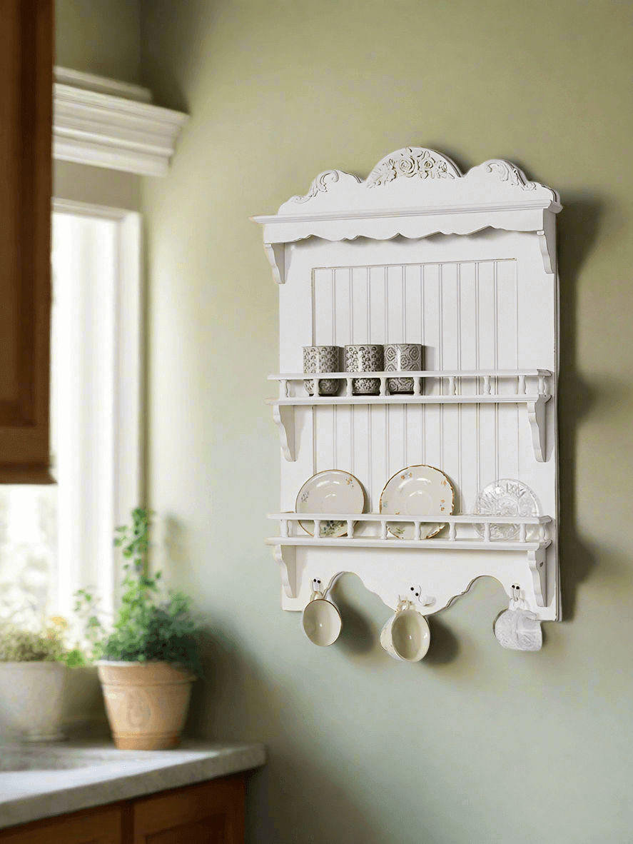 French country wall-mounted dish rack holding cups and plates against a green wall