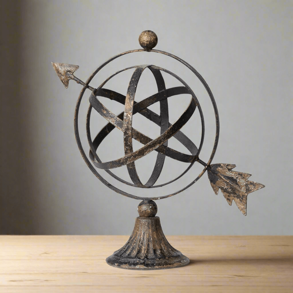 Antiqued iron armillary sculpture with an arrow on a wooden tabletop.