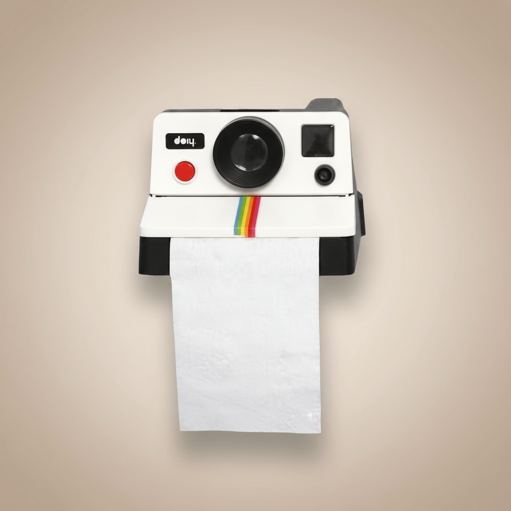 Polaroid camera-shaped toilet paper holder on a beige wall